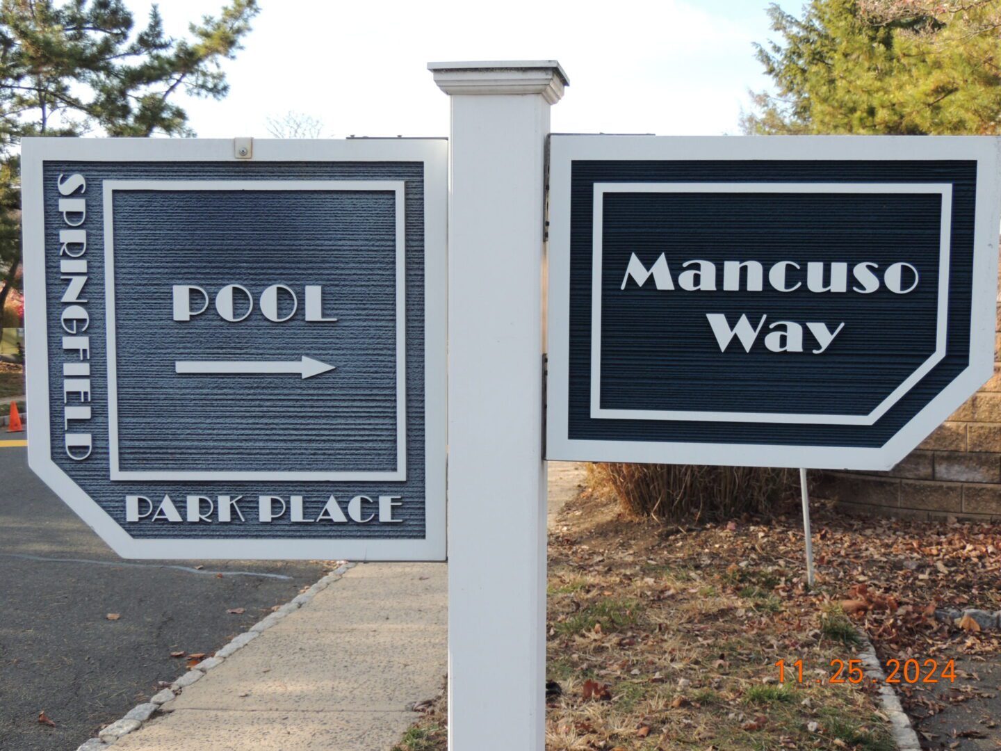Signs showing directions to "Springfield Park Place Pool" with an arrow and "Mancuso Way" in a residential area.