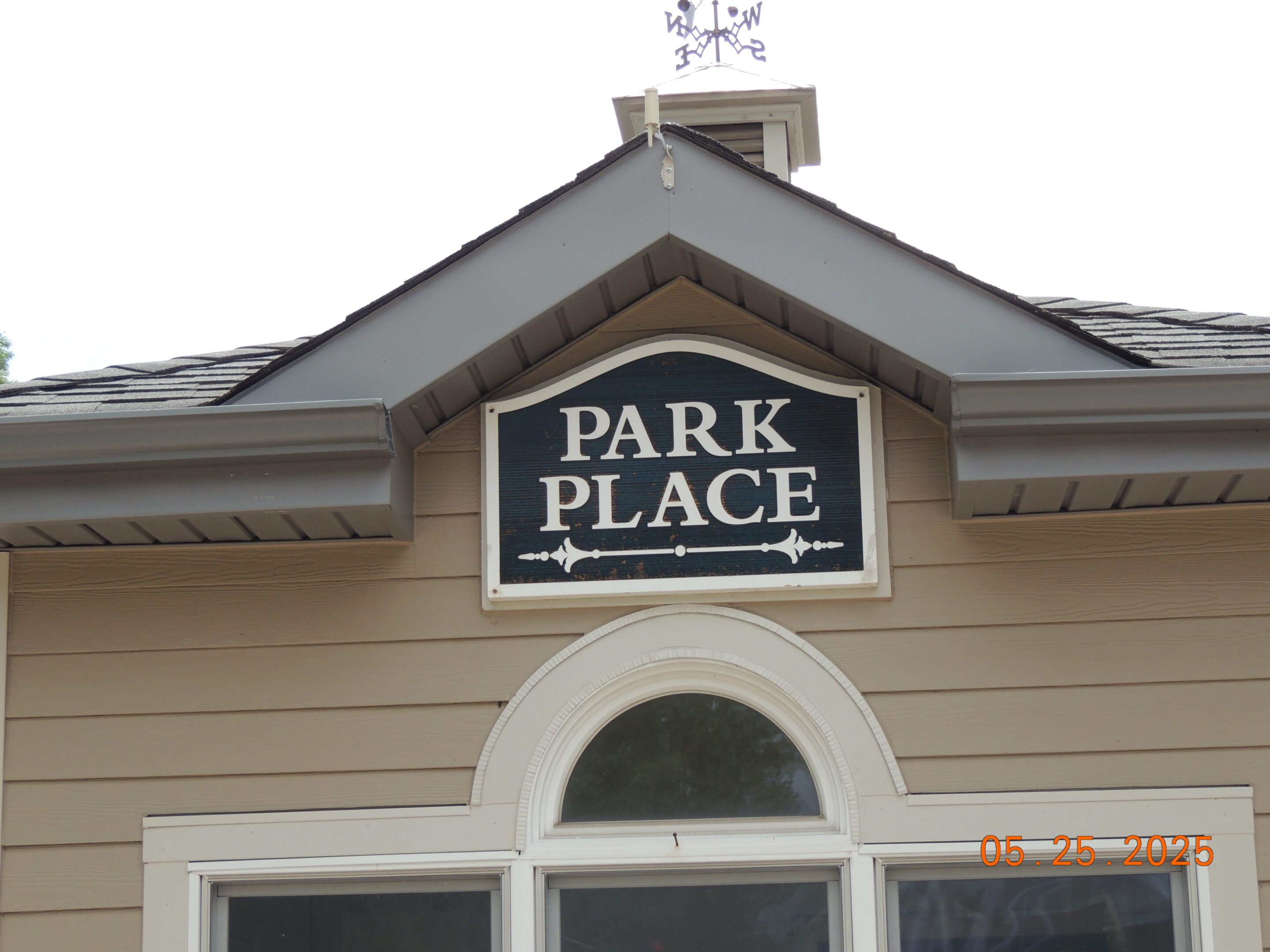 A sign reading "PARK PLACE" is mounted on the exterior of a tan building above a window; the photo is dated May 25, 2025.